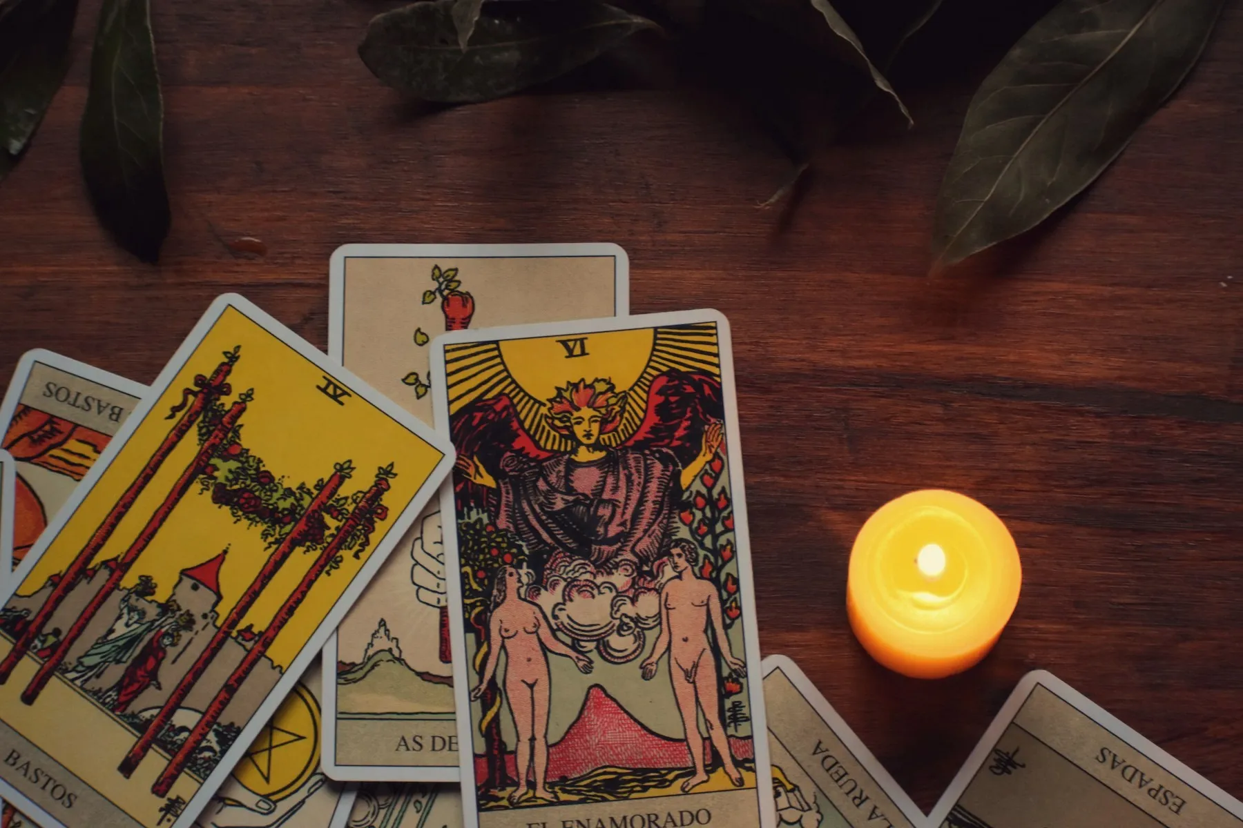Rider-Waite tarot cards beside a lit candle on a wooden table